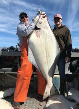 Captain Shane of Driftwood Charters in Homer, Alaska holds up Barndoor size halibut